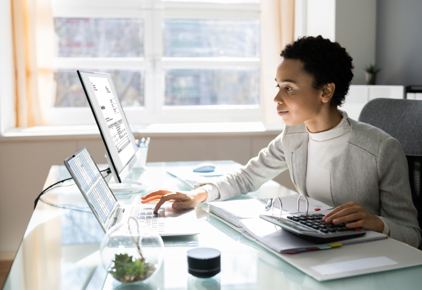 Image of employer in an office reading information on desktop computer about redundancy