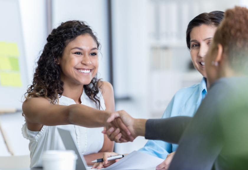 New employee shaking hands with employer over contract.