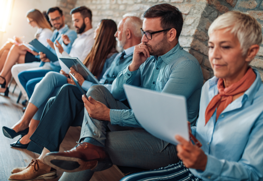 MAny job seekers sitting in a waiting room looking at job adverts