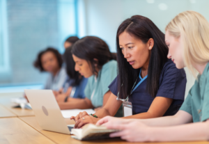 A number of age care professionals talking, taking notes and reading updated on their laptop computers