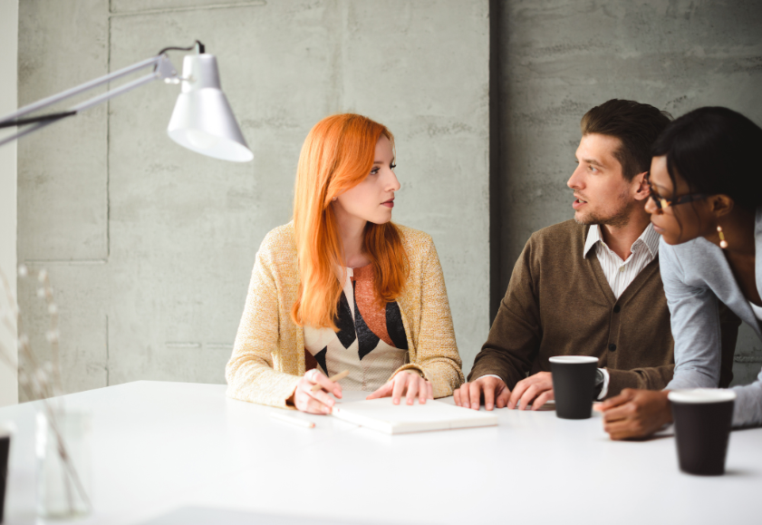 Three employees in an meeting room talking their resignation decision over