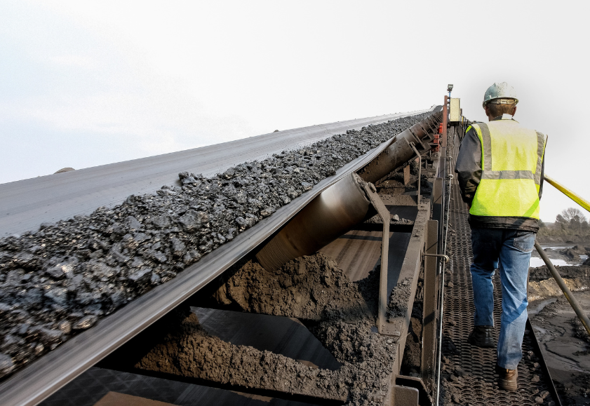 Coal worker next to a conveyer belt carrying coal